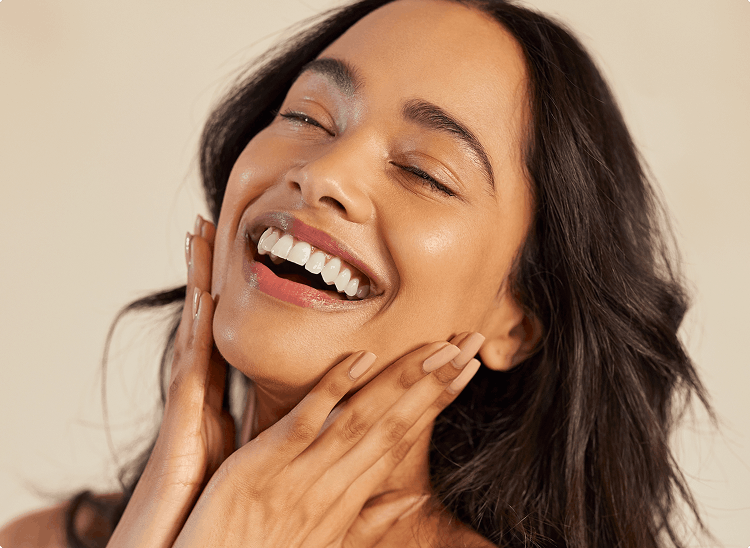 Joyful woman with glowing skin touching her face, suggesting confidence and effective skincare.