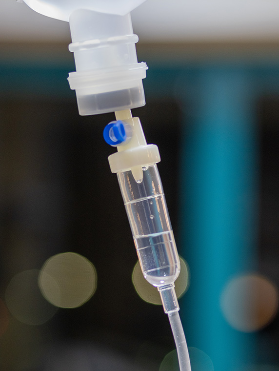 Close-up of IV drip chamber with fluid, highlighting intravenous infusion therapy in clinical setting.
