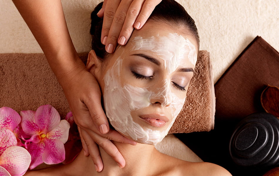 Woman with facial mask receiving spa massage, highlighting relaxing and rejuvenating skincare treatment.