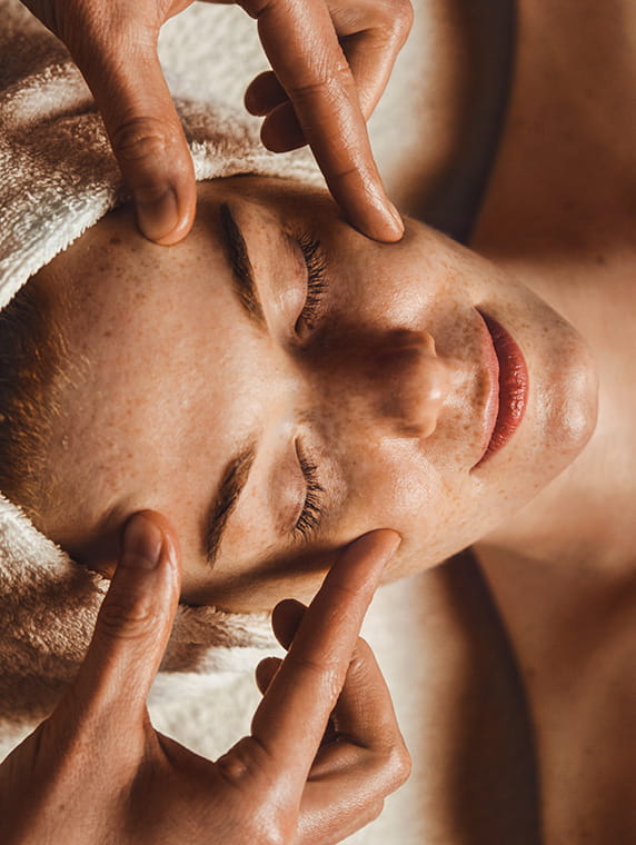 Esthetician performing facial acupressure massage on woman, highlighting relaxing professional skincare treatment.