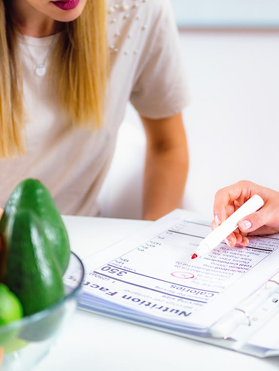 Nutritionist reviewing meal plan with client, highlighting calorie tracking and healthy eating guidance.