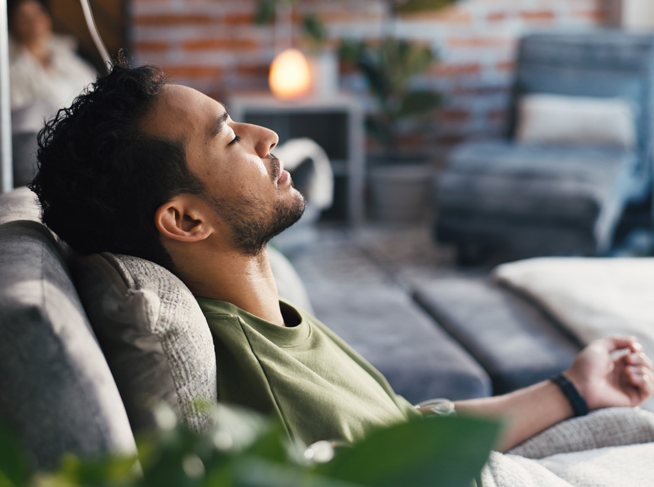 Man reclining with eyes closed in lounge, highlighting relaxation during wellness or IV therapy session.