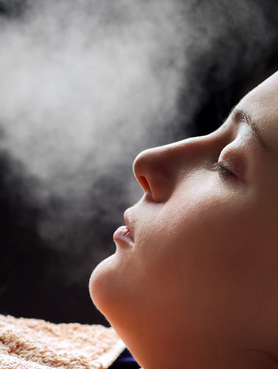 Woman with eyes closed exhaling visible vapor, highlighting breath in cold air or relaxation therapy.